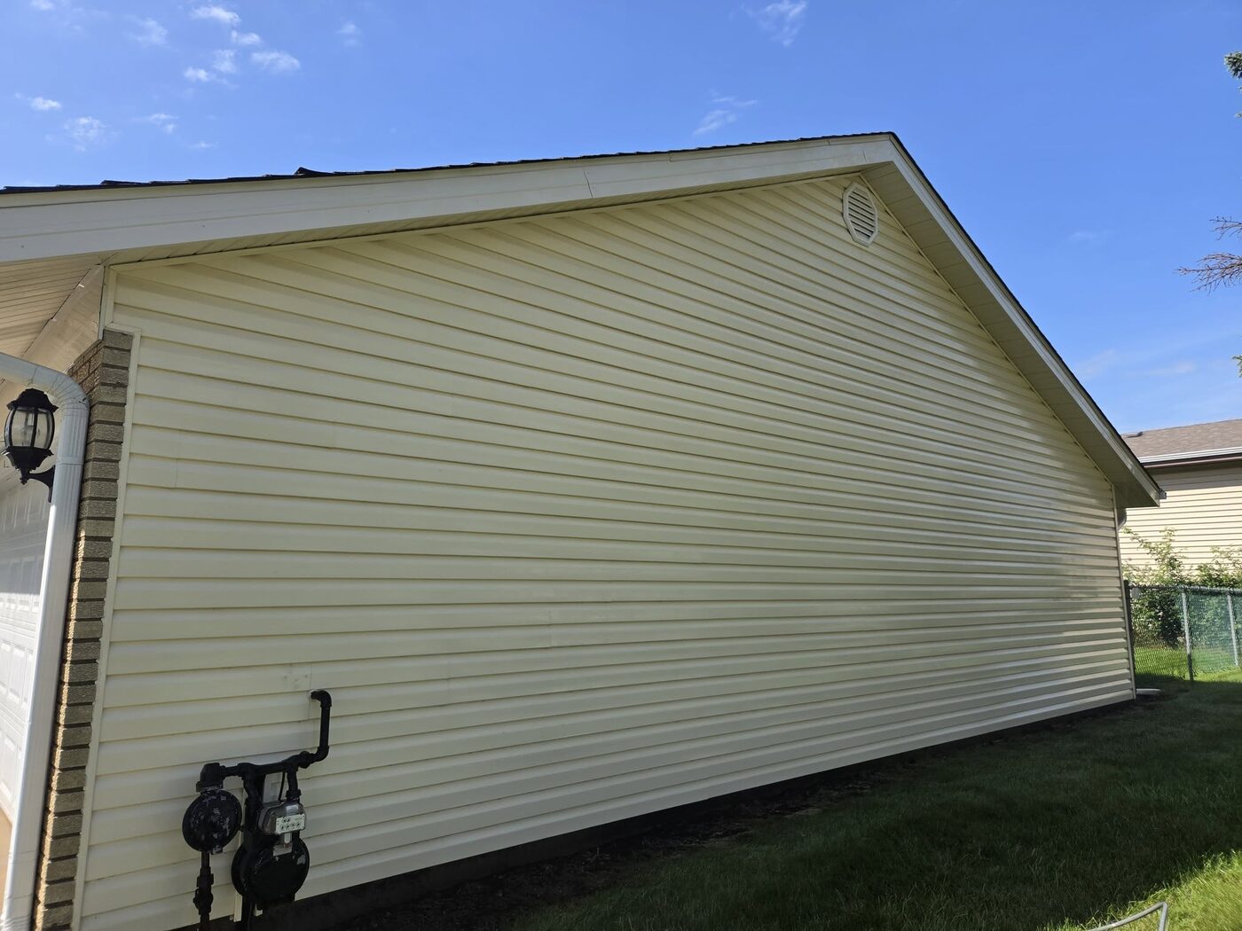 The same wall after a soft wash, the siding back to a clean even cream with no streaking left