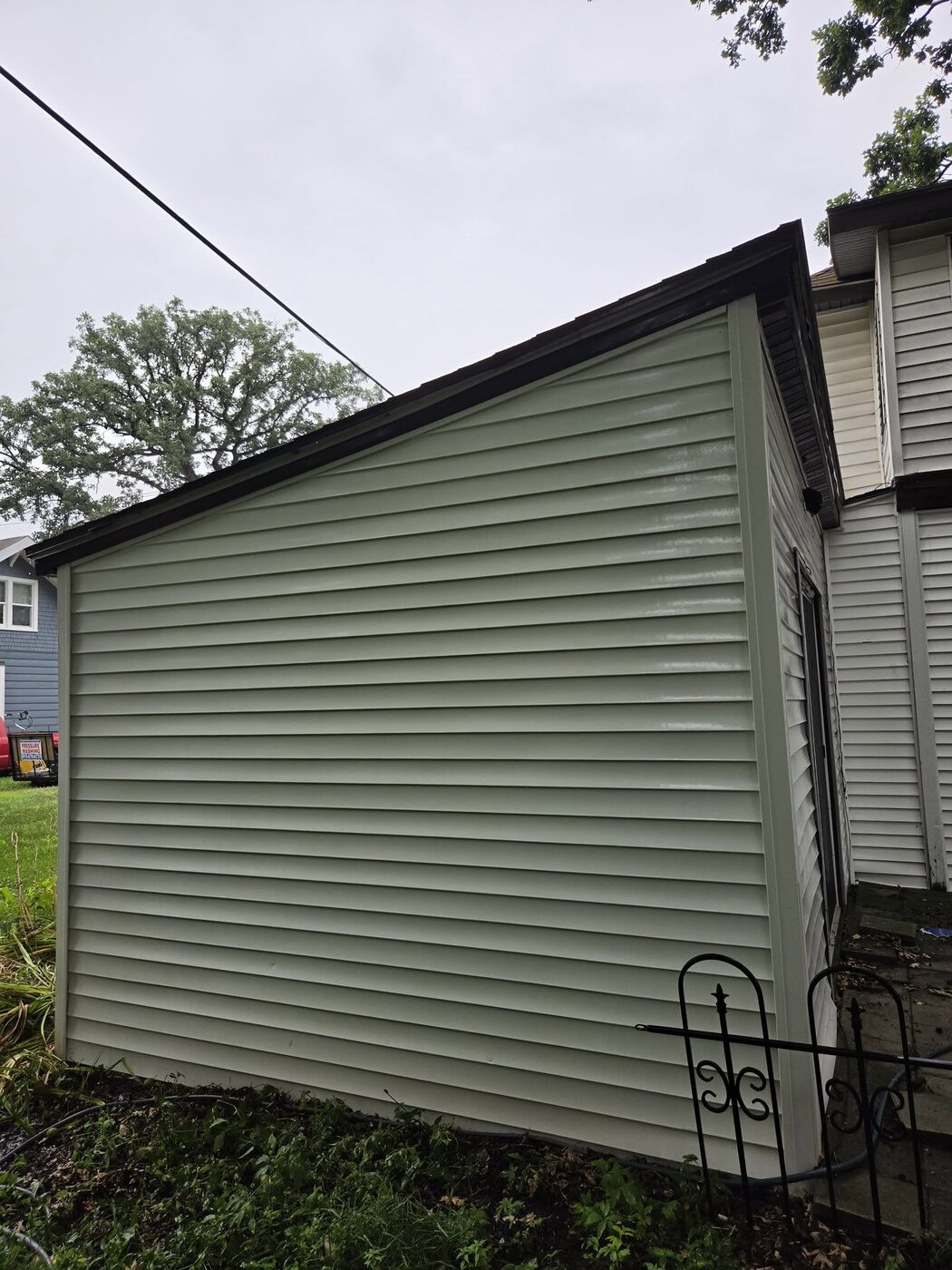 The same garage wall washed clean, the siding bright with the growth gone