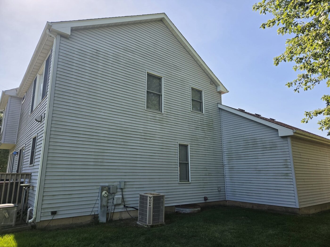 The back of a two storey house with siding dulled by dirt and algae