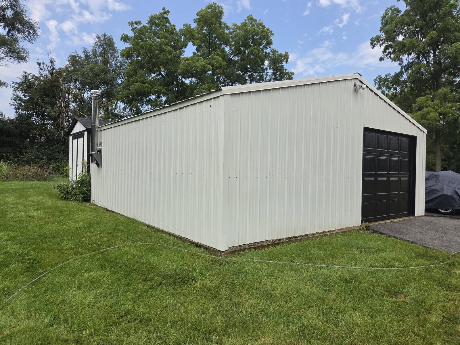 A large steel outbuilding with clean cream panels and a dark garage door