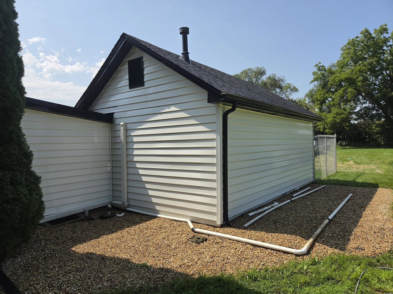 A detached garage with clean white siding and a dark roofline