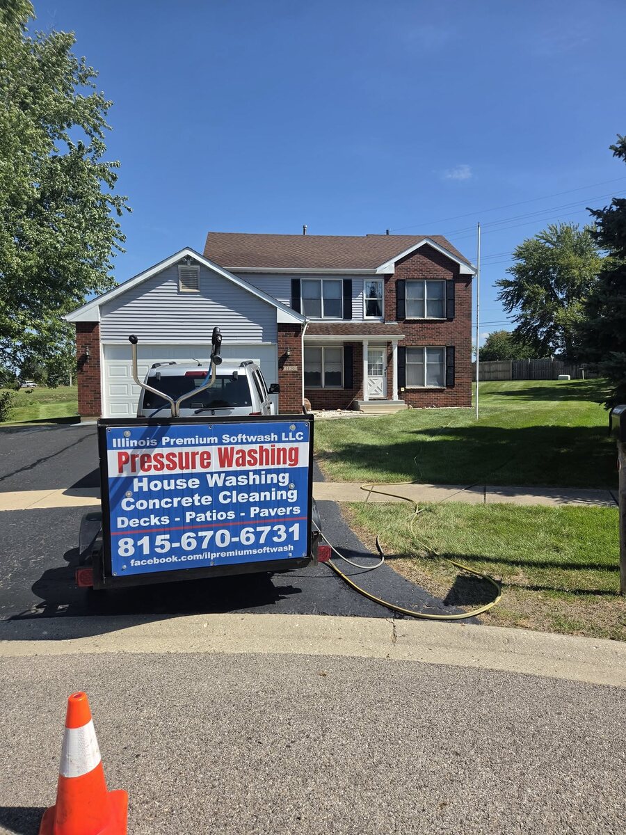 The Illinois Premium Softwash rig and sign parked in front of a customer's house on a job